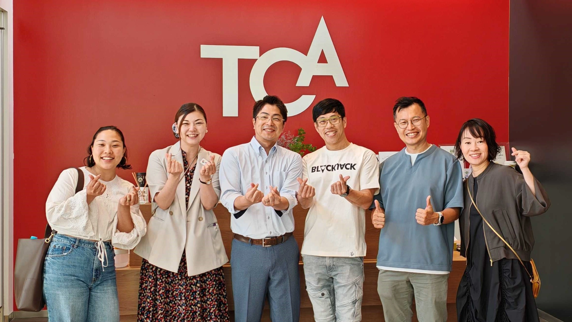 3dsense principal and vice principal with staff and agents at Tokyo Communication Arts College pose in front of the TCA wall.