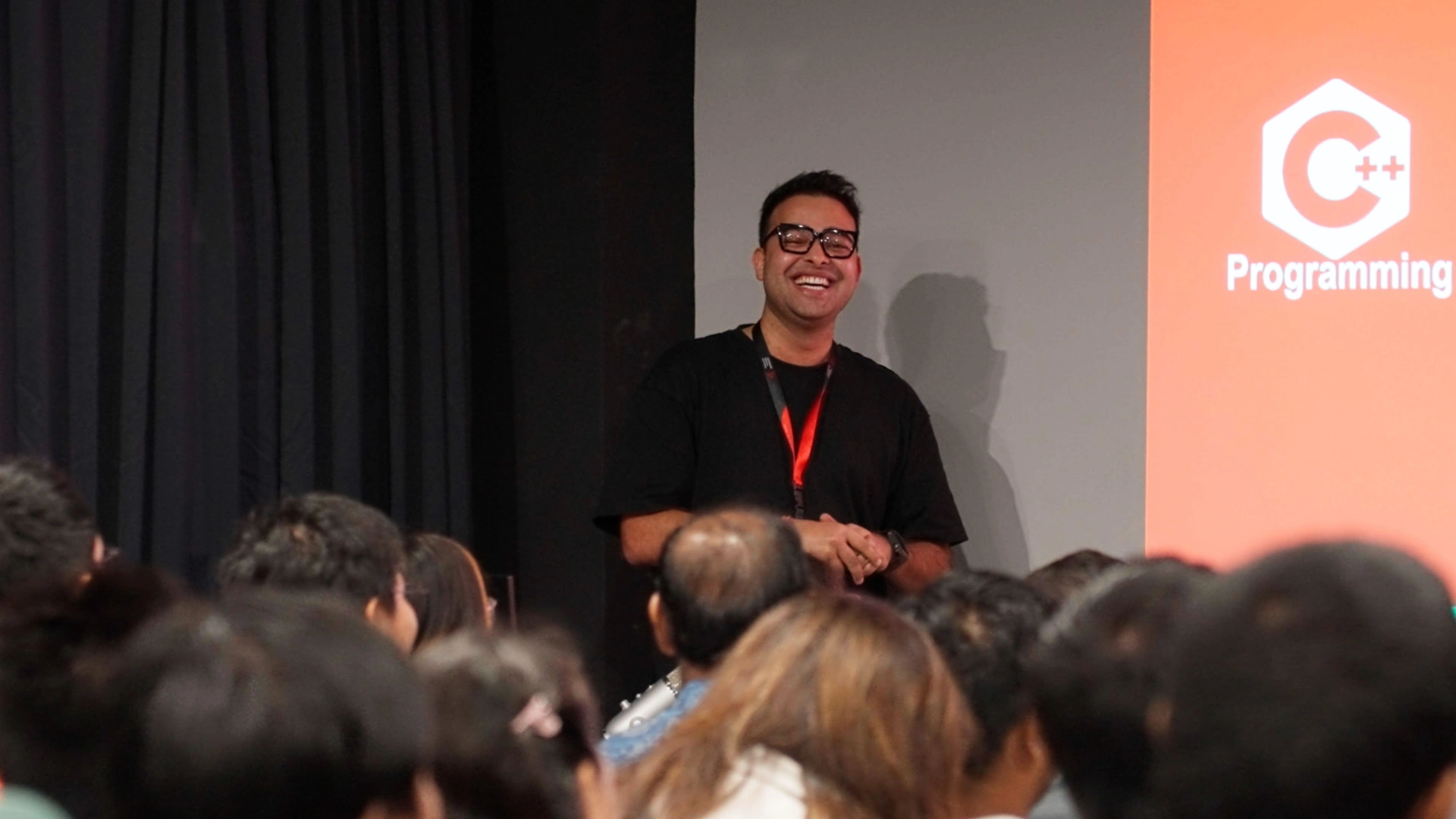 A motion design alumnus presenting to an audience, with a large screen showing the topic at 3dsense media school open house.