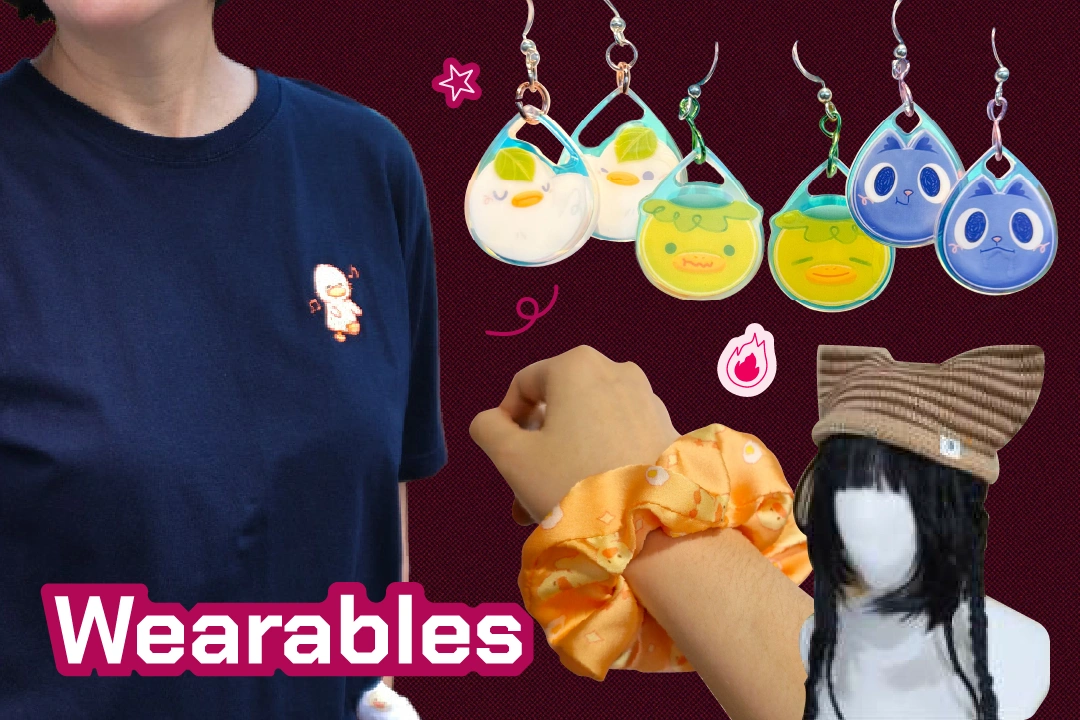 Collage of wearables: a navy shirt with a cute character, colorful earrings, black and red cat earrings, an orange scrunchie, and a brown cat-ear hat.
