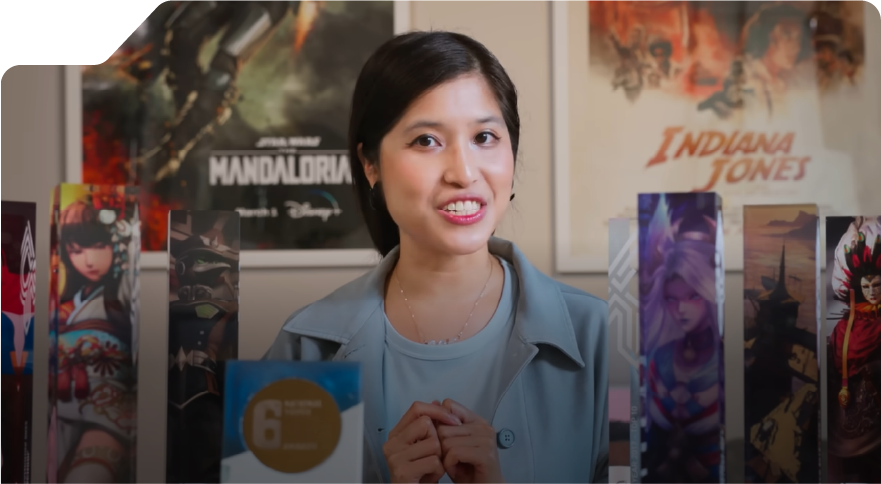 A person sits at a table surrounded by standing trophies from "The Rookies," with movie posters in the background.