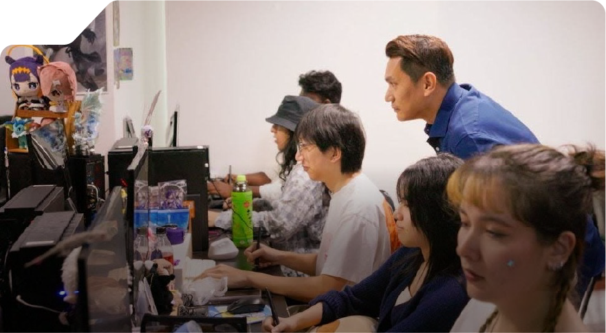 Students in classroom setting in front of their computer with lecturer overseeing them 